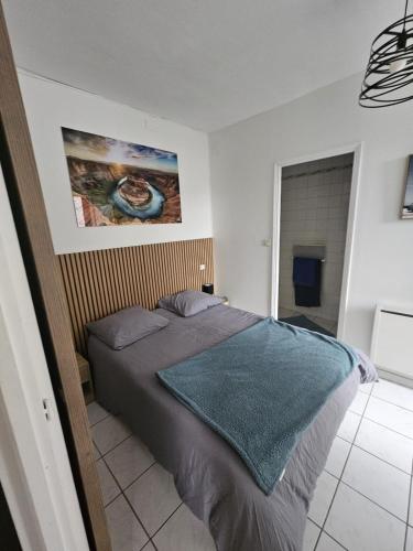 a bedroom with a bed with a blue blanket on it at F2 avec jardin in Nemours