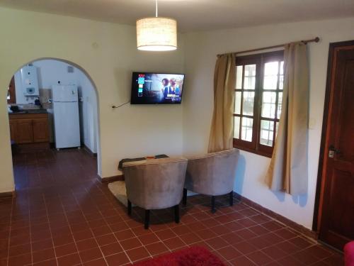 a living room with a table and a television on the wall at Casa Canela in La Cumbre