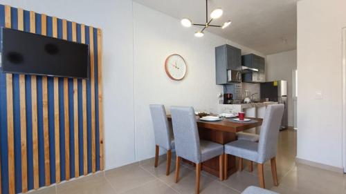 a dining room with a table and chairs and a clock at Cómodo y lindo departamento cerca de las playas in Mezcales