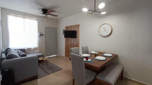 a living room with a table and a clock on the wall at Cómodo y lindo departamento cerca de las playas in Mezcales