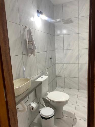 a white bathroom with a toilet and a sink at Casa dunas in Guajiru