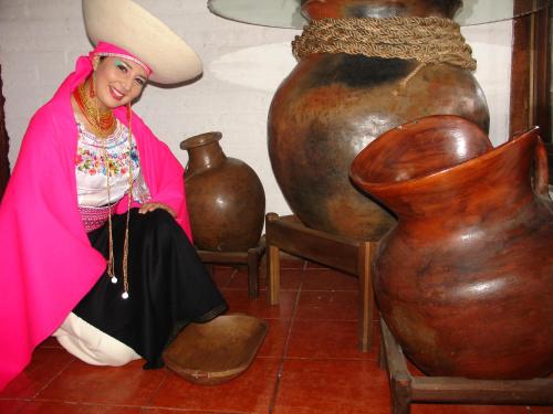 a woman dressed in a costume sitting next to a large vase at Hotel y Hosteria Natabuela in Natabuela