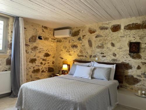 a bedroom with a bed and a stone wall at DOLONAS Cosy House in Aliyoí