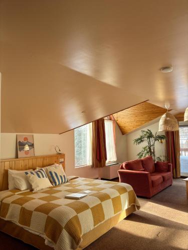 a bedroom with a large bed and a red chair at Auberge du Jardin in Petit-Saguenay