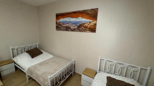 a bedroom with two beds and a painting on the wall at Apartament 11 Słoneczna in Ełk