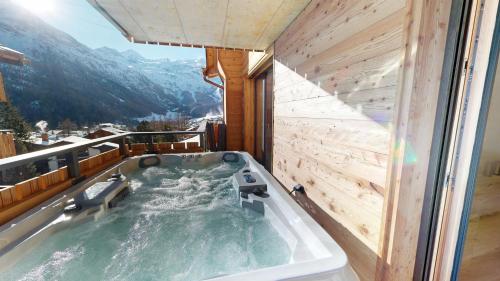 a jacuzzi tub on a balcony with mountains at Alphubel PEAK in Saas-Fee