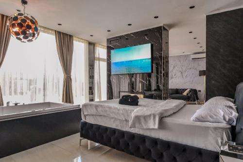 a bedroom with a bed and a tub and a television at Aura Villas Skopje in Skopje