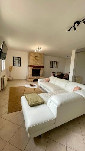 a living room with white couches and a fireplace at Le Gite Zoé in Bourbourg