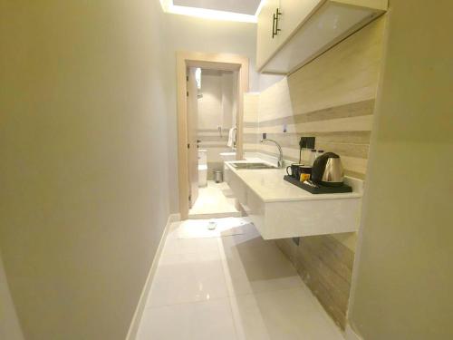 a white bathroom with two sinks and a mirror at النخبة الرفيعة للشقق المخدومة in Al Qurayyat