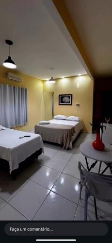 a hotel room with two beds and a table at Suíte prime in Monte das Gameleiras