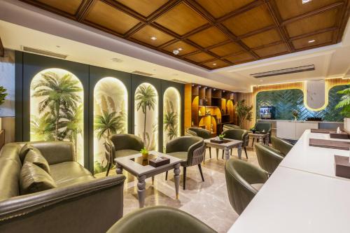 a waiting room at a hotel with green chairs and palm trees at The Delhi Dreams - A Luxury Hotel in New Delhi