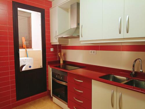 a kitchen with red walls and white cabinets and a sink at Casa Lili in Vélez-Rubio