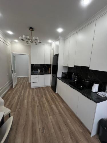 una cucina con mobili bianchi e pavimento in legno di STA Apartment a Bishkek