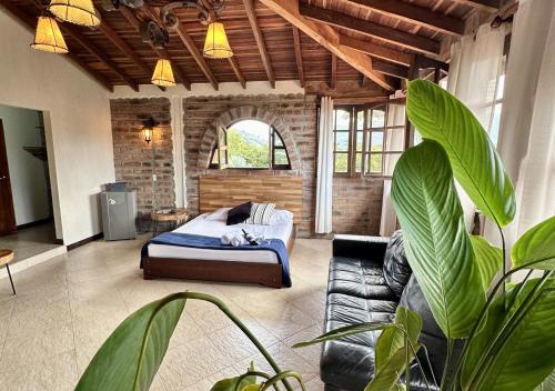 a bedroom with a bed and a couch and a plant at Finca Hotel Tierra Verde in Girardota