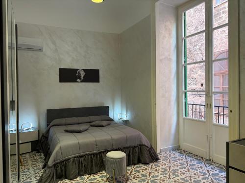 a bedroom with a bed and a large window at Elisir house in Palermo