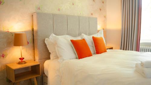 a bedroom with a white bed with orange pillows at 2 Bridge View in Selby