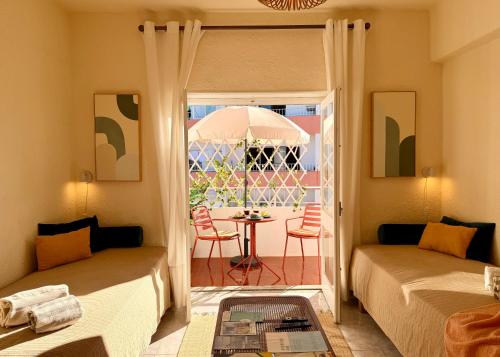 a room with two beds and a table with an umbrella at 2BR a 400m da praia Surf e Relax a 50min de Lisboa in Santa Cruz