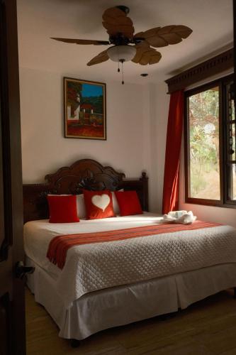 a bedroom with a bed with red pillows and a ceiling fan at Hotel Taa' Tiin in San Juan La Laguna