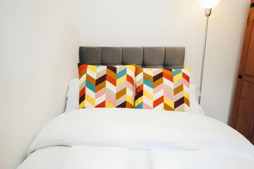 a white bed with a colorful pillow on it at 4 Bed House in Central Derby with Parking WiFi Smart TV in Derby