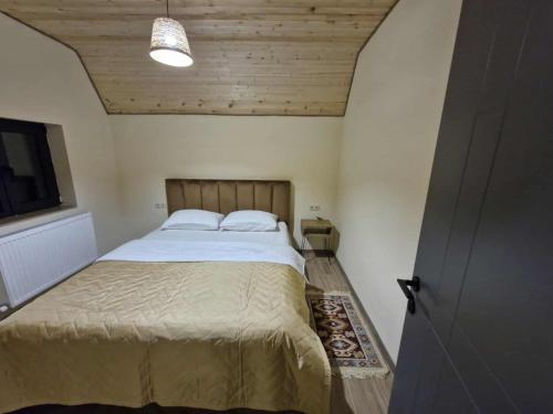 a bedroom with a bed and a wooden ceiling at kazbegi - Sno Mountain House in Sno