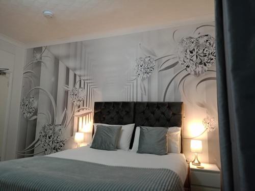 a bedroom with a large bed with flowers on the wall at Prestige Guest House Cambridge Modern Ensuite Rooms in Cambridge
