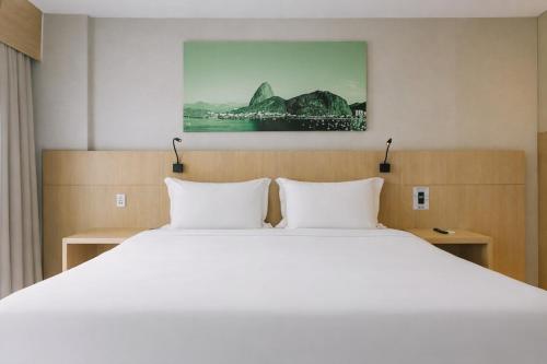 a bedroom with a large white bed with two pillows at Quality Rio de Janeiro - Barra da Tijuca in Rio de Janeiro