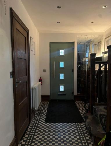 a hallway with a green door and a tile floor at SantalijsHoteliers Ltd in Leicester
