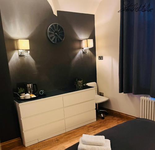 a bedroom with a dresser and a clock on the wall at SantalijsHoteliers Ltd in Leicester
