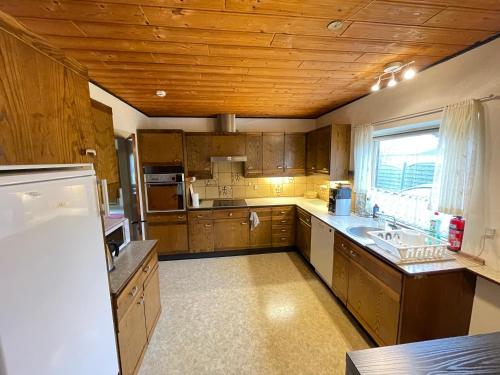 a large kitchen with wooden cabinets and a sink at 4-bedroom family villa, bath tub, billiards, piano, and fun board games in Rødby