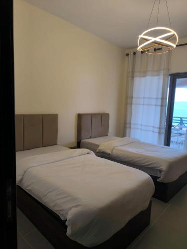 a room with two beds and a chandelier at EP1 TWO BEDROOM APARTMENT AT Samarah Resort in Sowayma