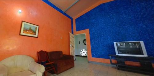 a living room with a blue wall and a tv at Villa Tahiti in Palmira