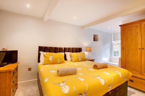 a bedroom with a yellow bed and a tv at 2 Bed in Kettlewell oc-ds985 in Kettlewell