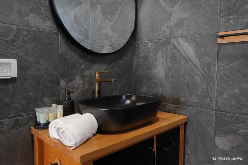 a bathroom with a black sink and a mirror at וילת היוצר in Ya‘ara