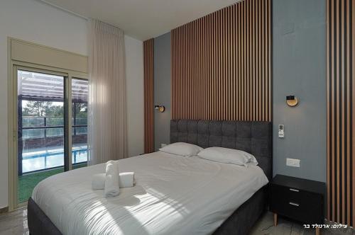 a bedroom with a large bed with a large window at וילת היוצר in Ya‘ara