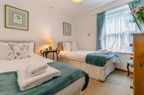 two beds in a room with a window and a bedskirts at 3 Bed in Porthleven oc-7bayvi in Porthleven