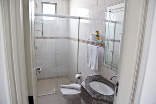 a bathroom with a toilet and a sink and a shower at Apart Hotel Bhally INN in Balneário Camboriú