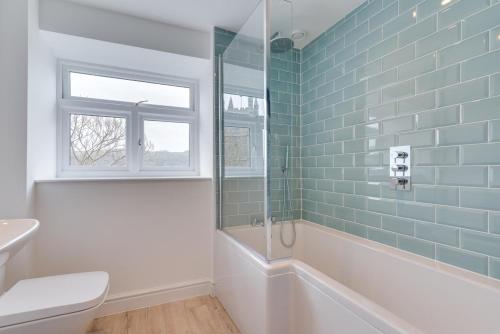 a bathroom with a tub and a toilet and a window at 3 Bed in Fowey oc-1cobbs in Fowey