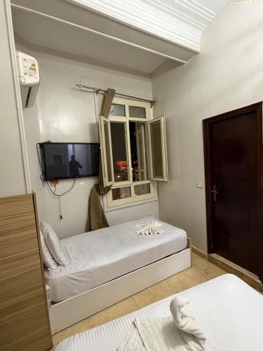 a bedroom with two beds and a tv and a window at Abdeen Cairo Hostel in Cairo
