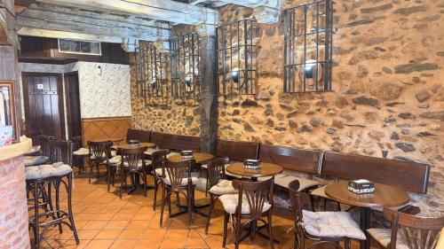a restaurant with tables and chairs and a stone wall at Hotel Rural La Posada de Lía in Berzocana