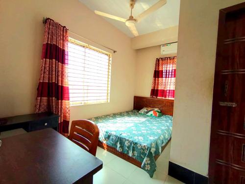 a bedroom with a bed and a table and a window at Hotel Relax Residential in Khulna