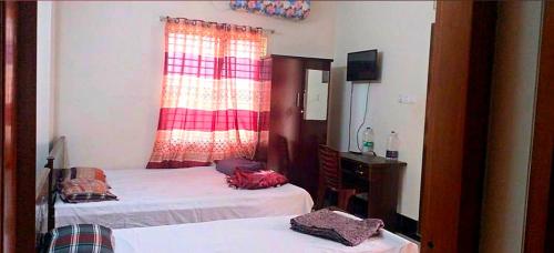 a bedroom with two beds and a dresser and a window at Hotel Relax Residential in Khulna