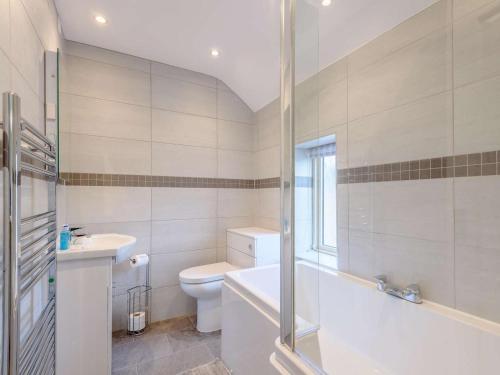 a bathroom with a tub and a toilet and a sink at 4 Bed in Bakewell oc-pk911 in Bakewell