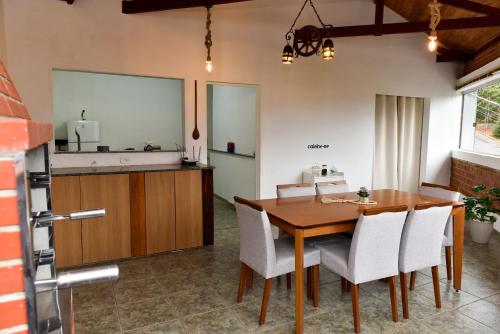 a kitchen and dining room with a wooden table and chairs at Paraiso Mantiqueira in Paraisópolis