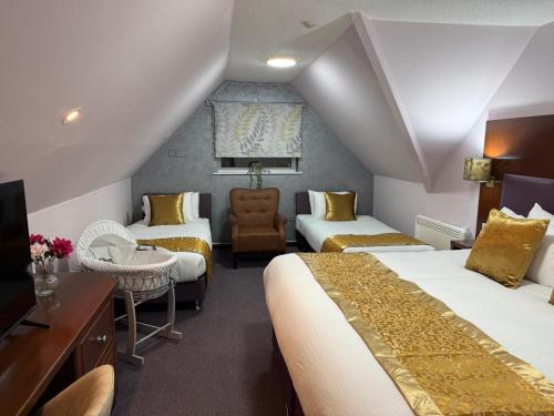 a hotel room with two beds and a chair at Quality City Hotel Restaurant Free Parking in Upton Warren