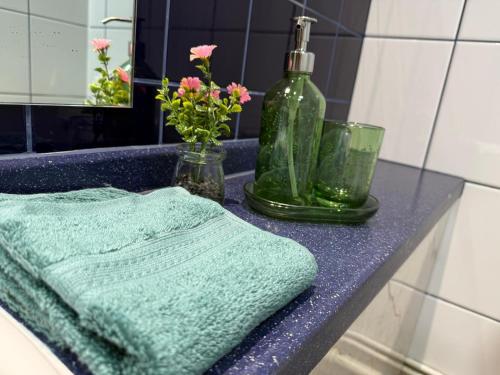 a bathroom sink with a green towel and flowers on it at Quality City Hotel Restaurant Free Parking in Upton Warren