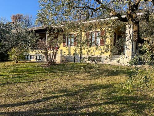 a yellow house with a tree in front of it at Villa Cà Bottura agli ulivi in Bardolino