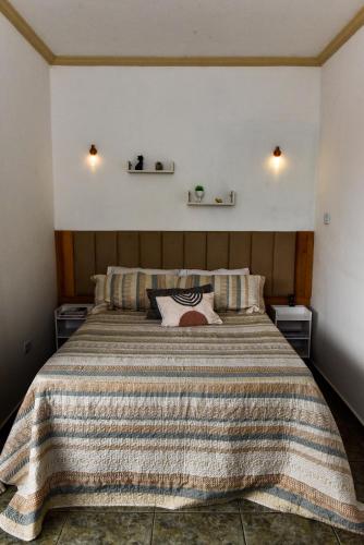 a bedroom with a large bed with a striped blanket at Paraiso Mantiqueira in Paraisópolis