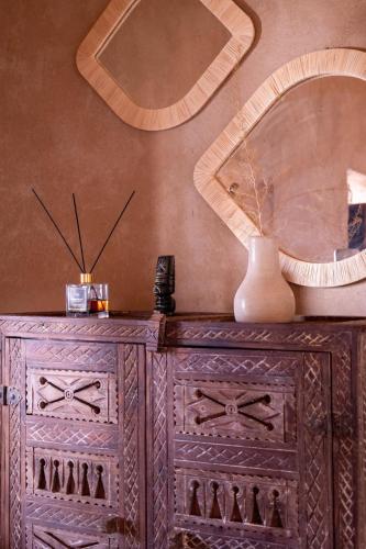 a wooden dresser with a mirror on a wall at Muma Lodge in Bouihat