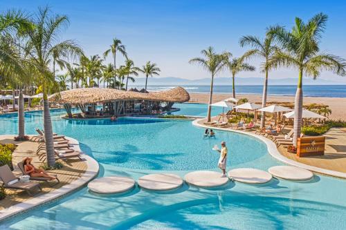 a resort pool with palm trees and a beach at BON Hotel at VidantaWorld Nuevo Vallarta in Nuevo Vallarta