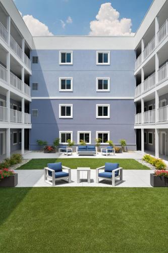 a rendering of a large apartment building with benches at stayAPT Suites Hampton in Hampton